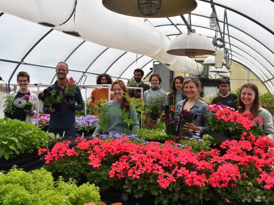 a group of people standing behind a table of poinsettias smiling at the camera