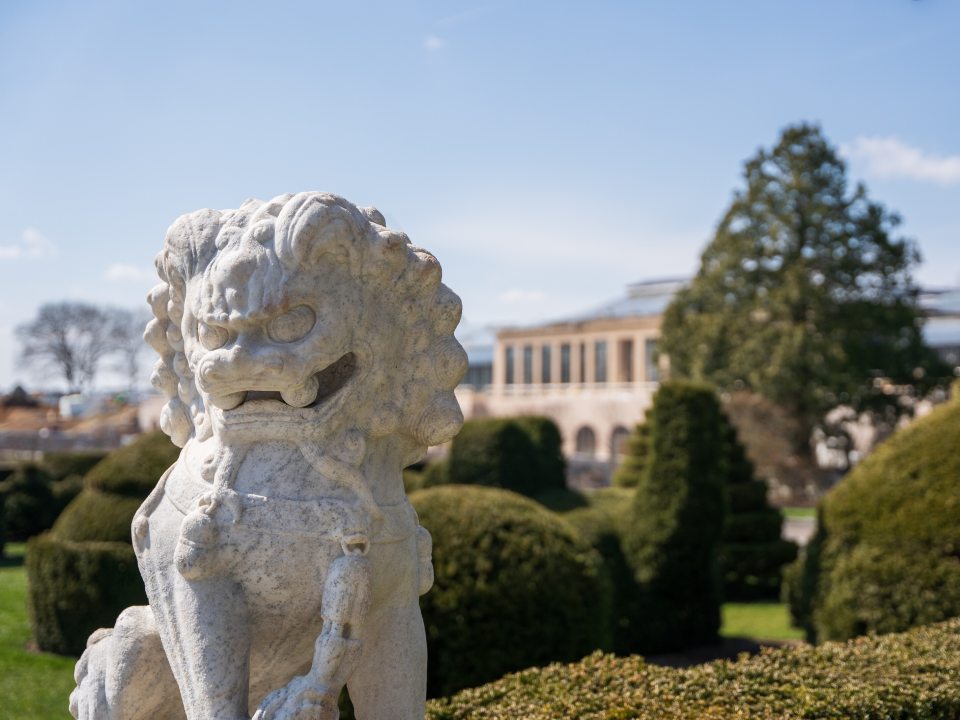 a statue of a foo dog in front of topiary trees