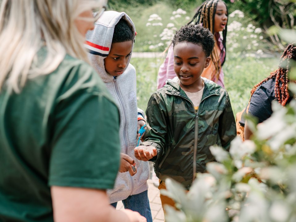 Two student holding out their hands in a nature setting.