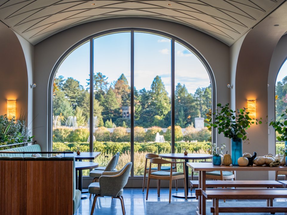 The interior of a restaurant featuring white arched ceilings and wood furniture. 