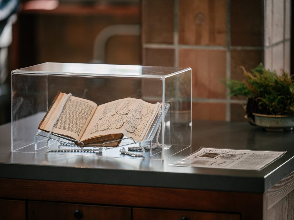 A book propped open, placed under a glass case. 