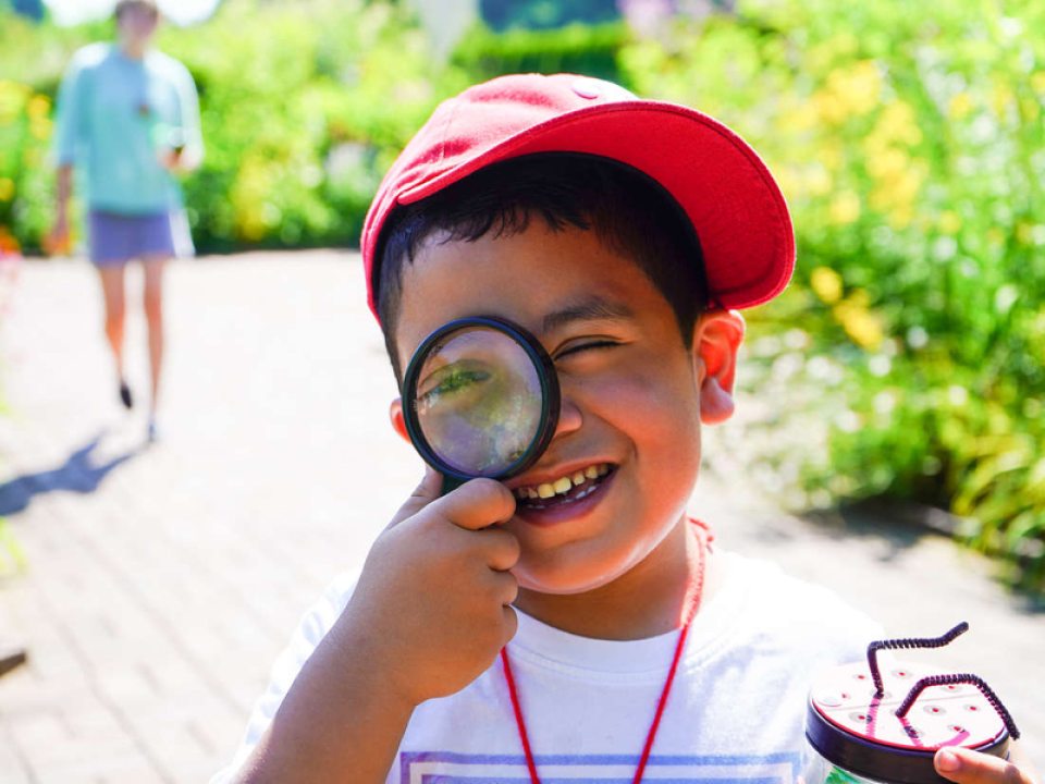 a small boy holding a magnifying glass up to his eye
