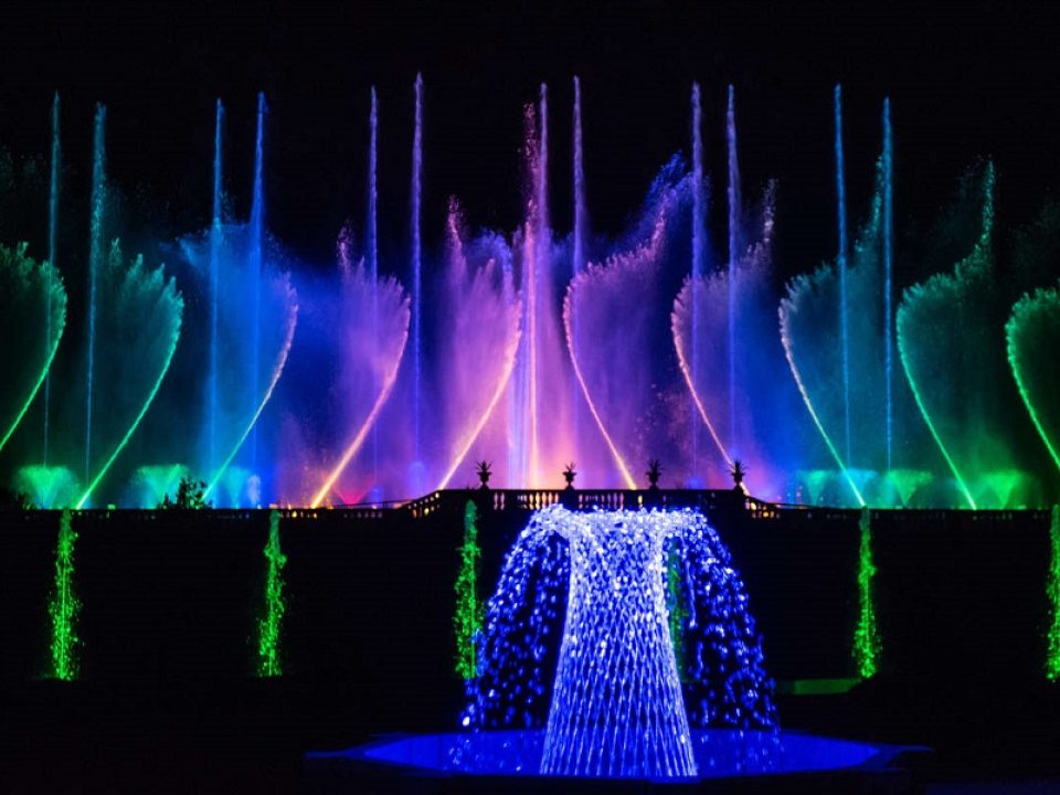 a wall of fountains that glow colors of green, blue, purple, and pink 