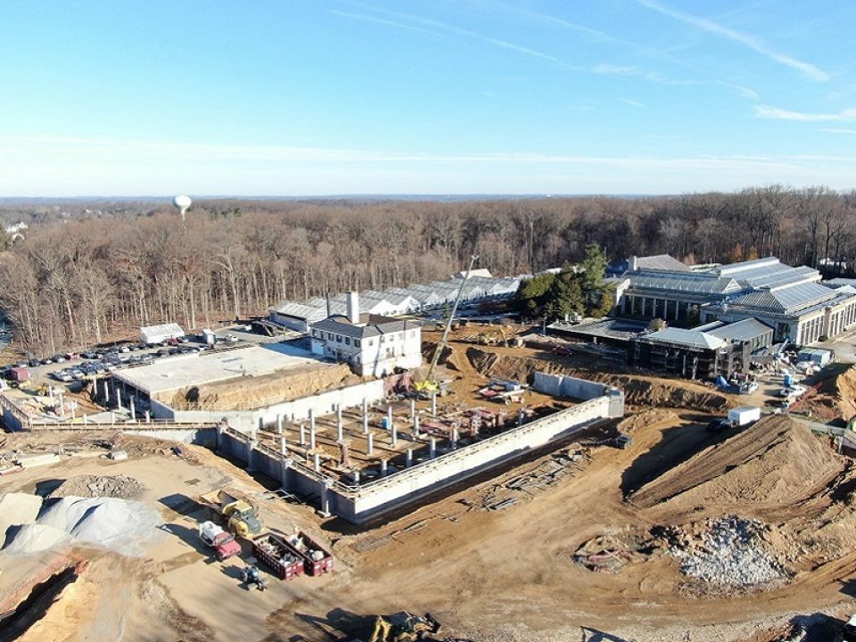 a heavy construction area with a start of a new building in the middle and surrounded by dirt mounds and trucks