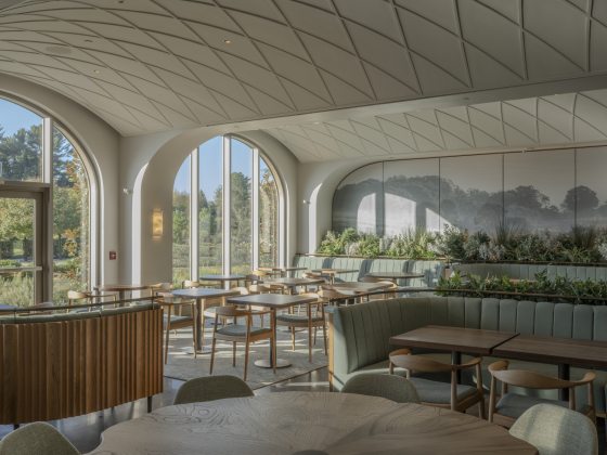 Interior shot of dining space with green booths, wood tables, and arched windows and ceiling