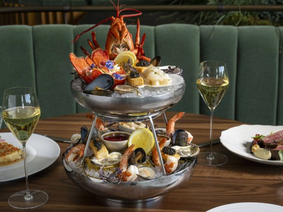 Double layer seafood serving dish, with wine glasses and individual plates.