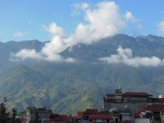 a green mountain with a city below 