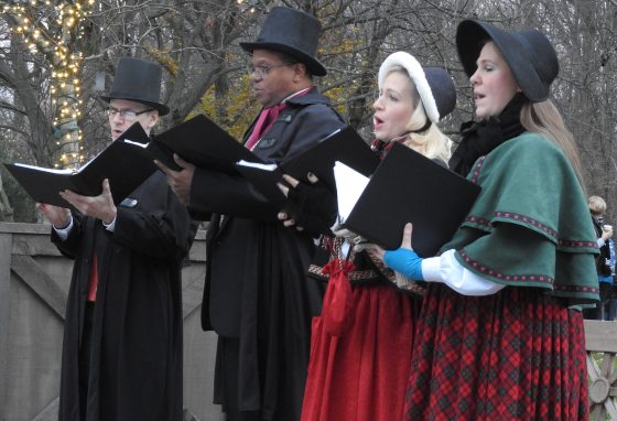 four people holding books and singing outside 
