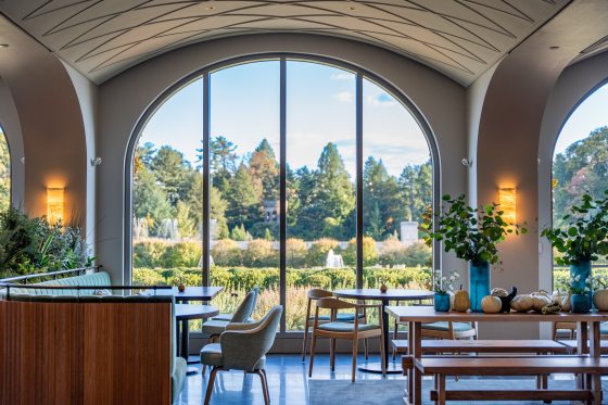 The interior of a restaurant featuring white arched ceilings and wood furniture. 