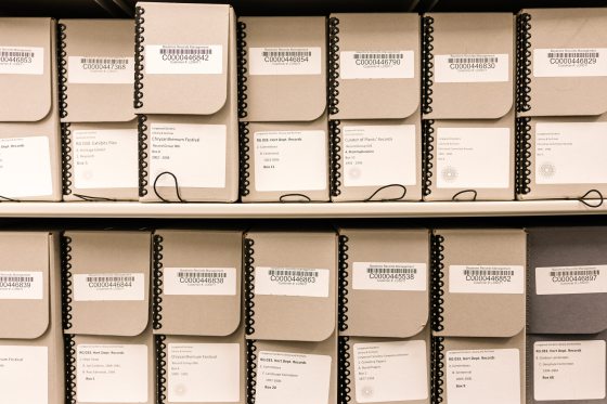 Tan numbered archive boxes aligned on a shelf.