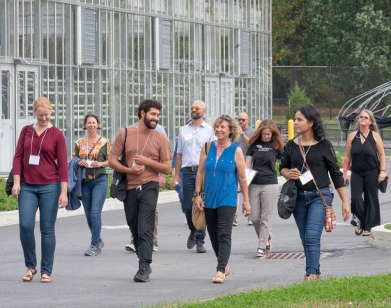 a group of people smiling and walking next to a glass greenhouse 