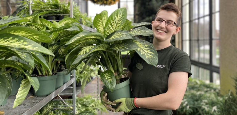 a person holding a plant and smiling for the camera 