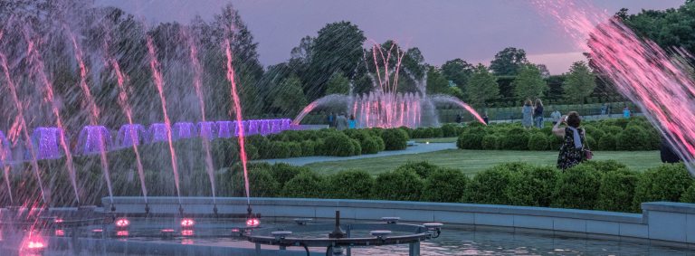 pink and purple colored water jets out of fountain garden against a cotton candy sunset