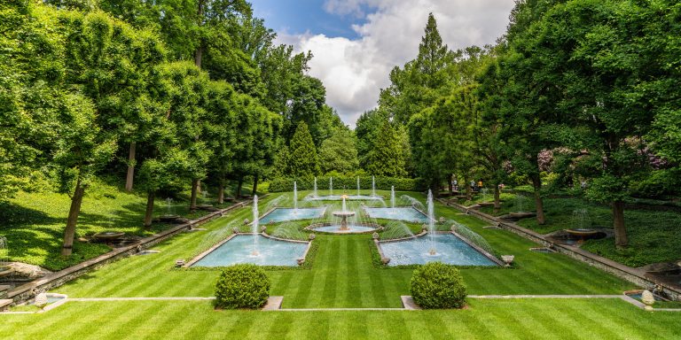 Fountains dance in blue pools on a freshly mowed green lawn