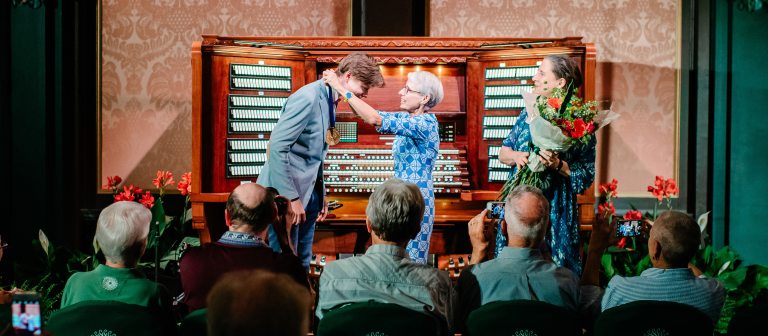 two people presenting the winner with a medal and flowers