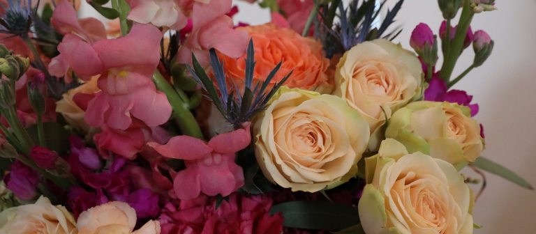 bouquet of flowers containing white roses and pink and oranges blooms
