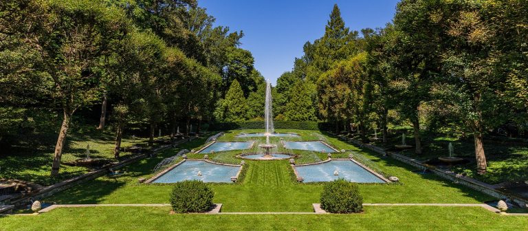 an Italian inspired garden with several fountains and green lawns