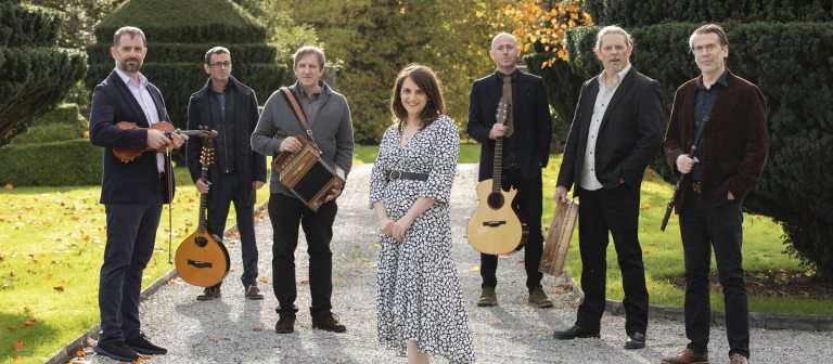 Seven adults standing outside holding instruments.