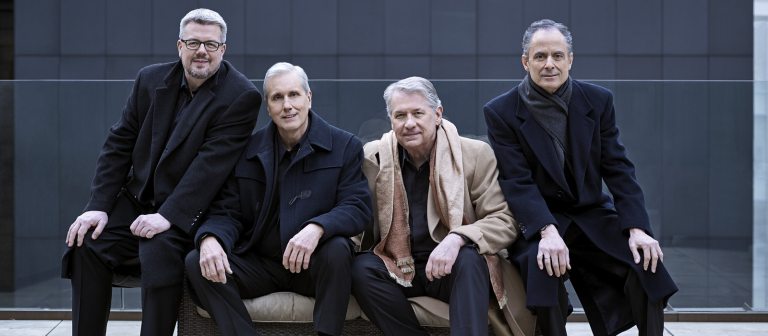 Four adults sitting on a bench.