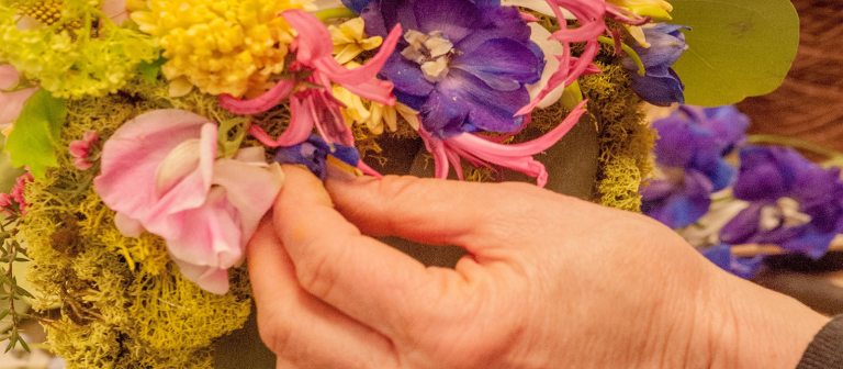 a hand of a person arranging flowers