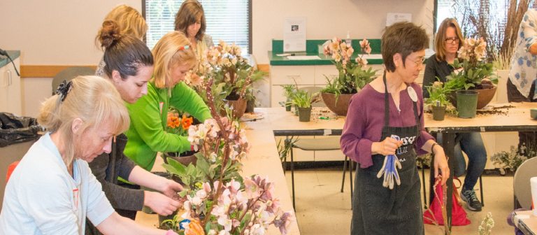 person leading a floral design class with several students facing them