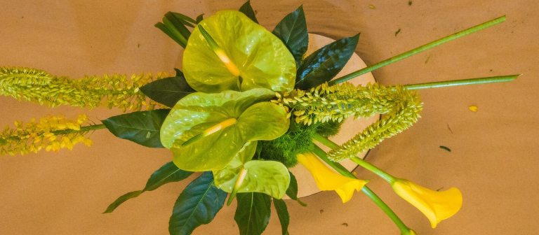 floral arrangement with green leaves and yellow lilies photographed from above