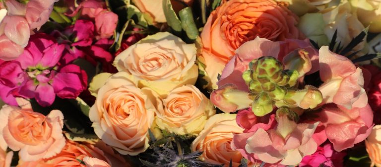 a close up image of a floral bouquet with pink, white, and peach colored flowers