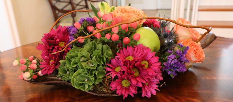 low and oblong cut flower arrangement featuring bold pinks, greens, and orange colors