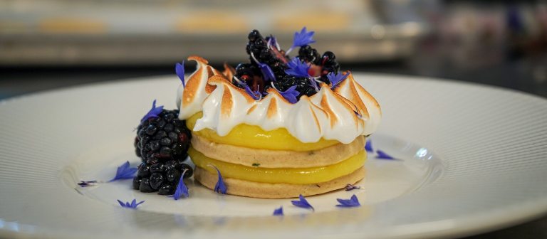 a lemon tart with blueberries on a white plate