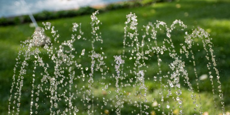 water fountains rising from the ground amid a green grass backdrop