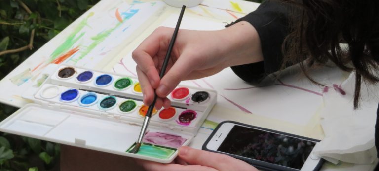 Person mixes watercolors in a tray
