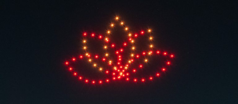 orange and red drone lights form a lotus shape against a black sky