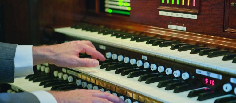 closeup of organ console, with hands on the keys