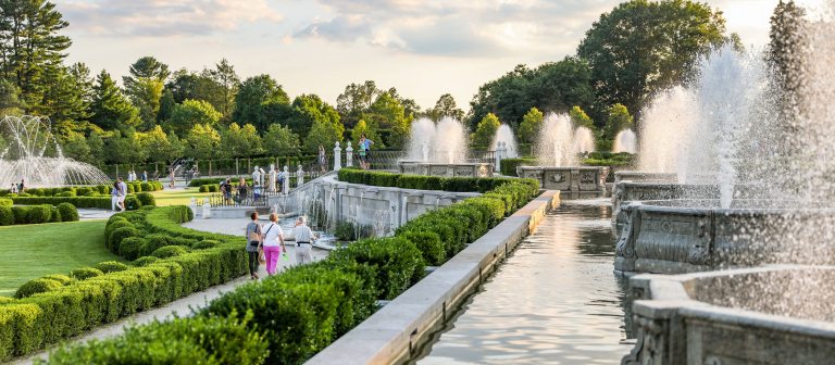 people of all ages stroll through a fountain garden