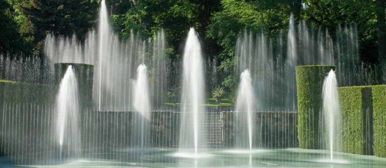 fountains rising from a stage surrounded by garden greenery
