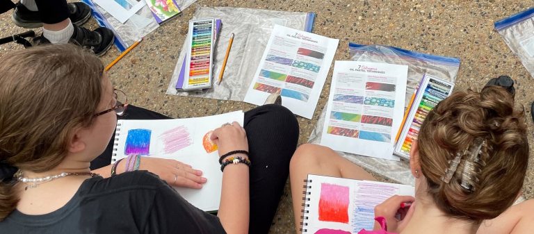 2 girls using oil pastels on paper