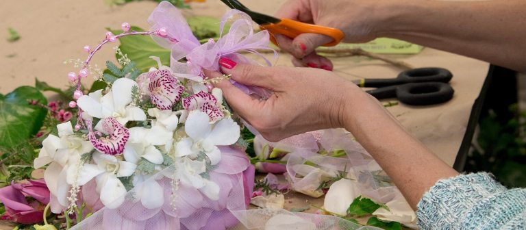 A person working on a floral bouquet, holding a pair of scissors.
