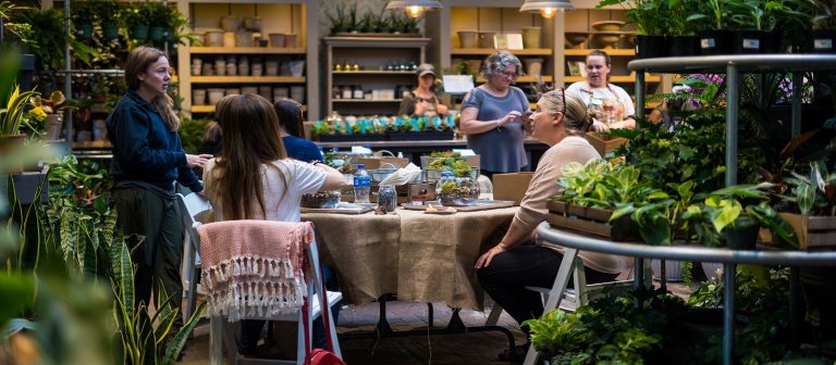 People sitting around a table in a plant shop doing a workshop.