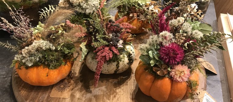 Flower centerpieces on a table using pumpkins as the base.