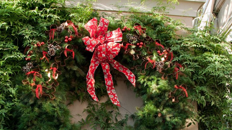 Top half of a green wreath with a red bow.