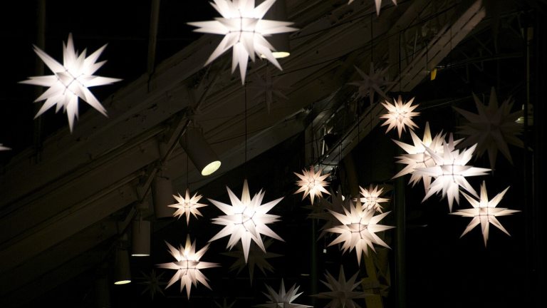 A night sky with white lit star ornaments.