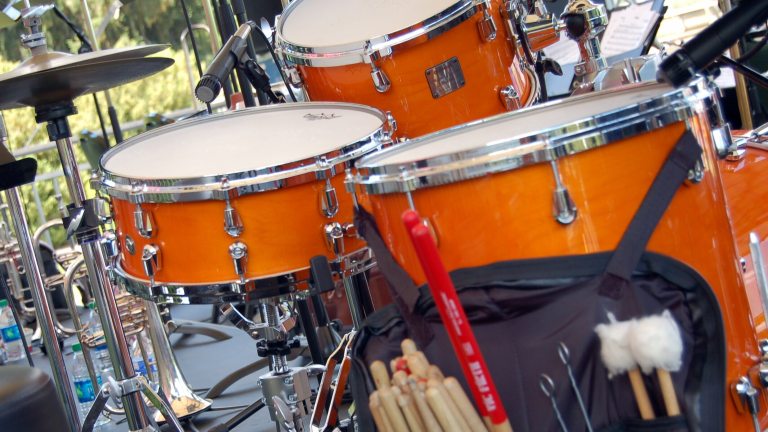 Closeup of trio of orange drums in a drumset.