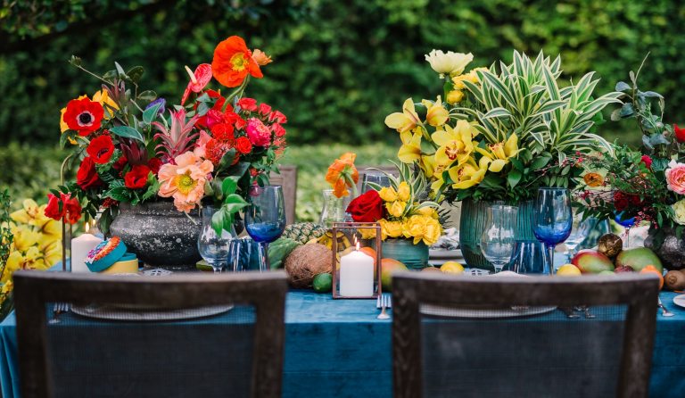 An outdoor table decorated with large tropical floral displays. 