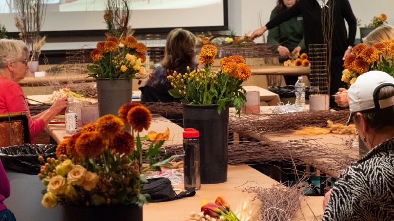 People sitting at tables preparing to create a floral design.
