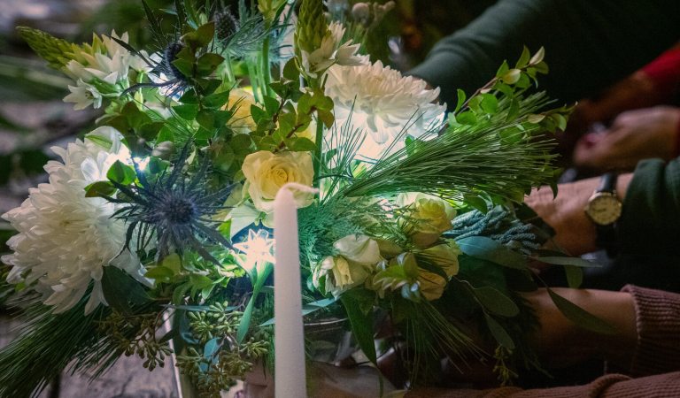 A person creating a floral arrangment from white and yellow flowers.