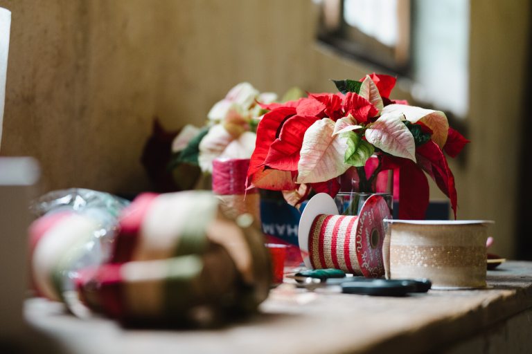 A table with a multi-colored poinsettia and craft supplies on top.