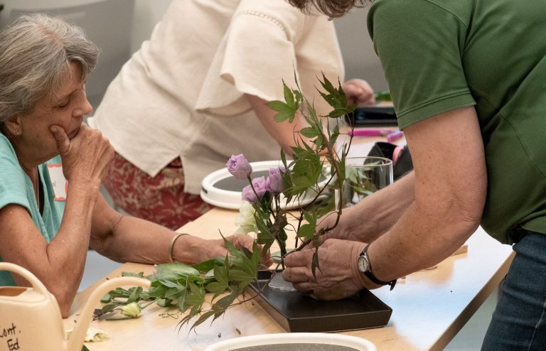People around a table creating a floral arrangement.