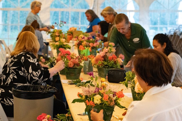 People seated at a table creating floral arrangements.
