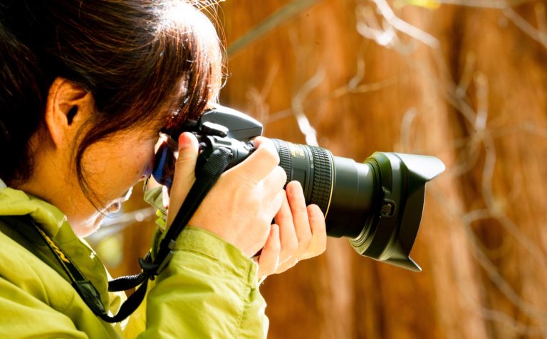 An up close image of a person holding a camera aiming to take a photograph.
