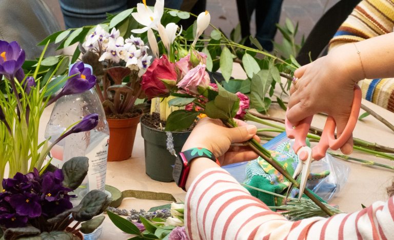The arms of a person creating a floral arrangement.